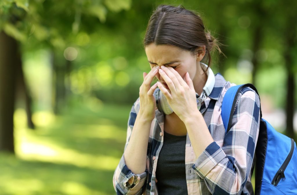A young woman rubbing her eyes due to allergies