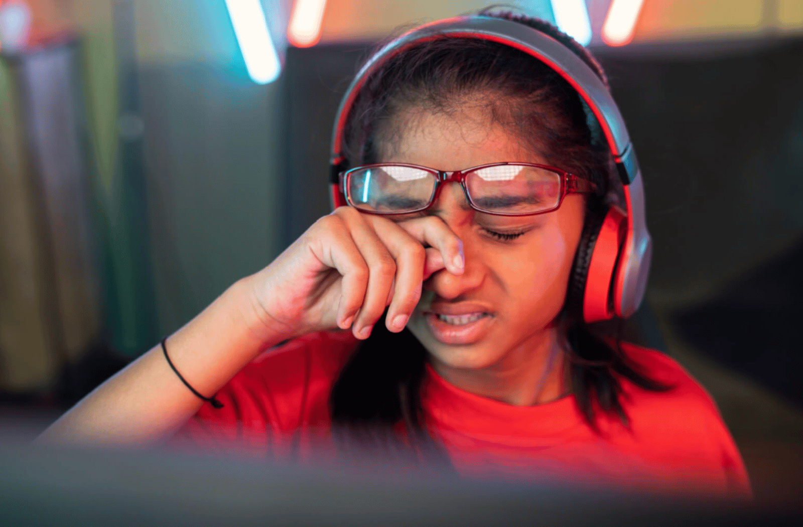 A young girl is rubbing her tired itchy eyes, she experiencing eye strain due to playing video games for a long period of time
