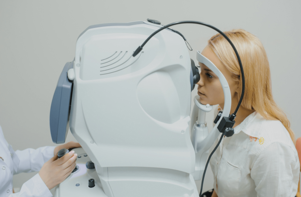 A young woman is looking through a machine that provides a detailed view of her eye’s structure to measure her pupil and iris.