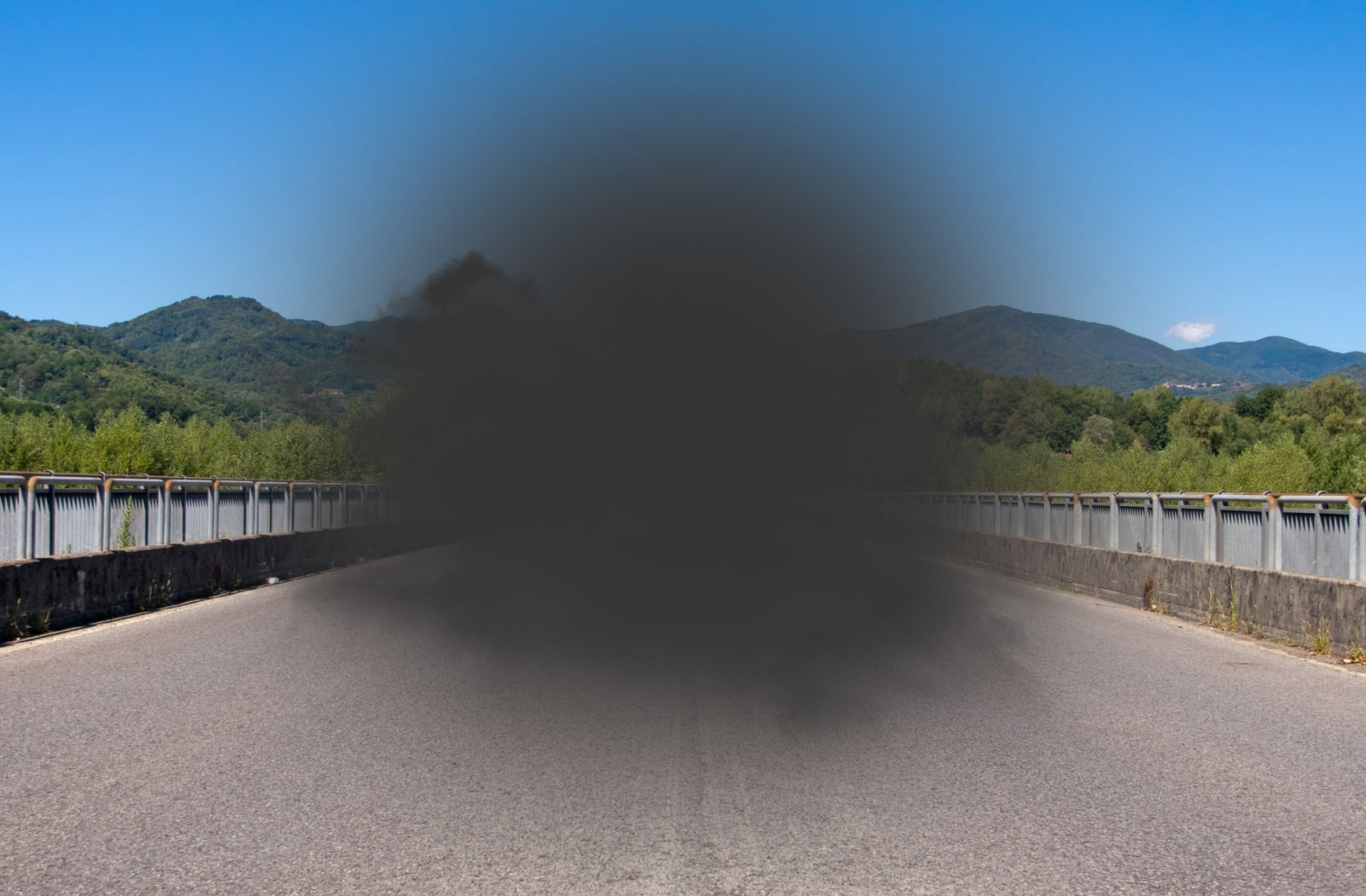 A view of a concrete bridge on a sunny day with a dark grey spot blocking central vision, representing the POV of a person with dry macular degeneration.