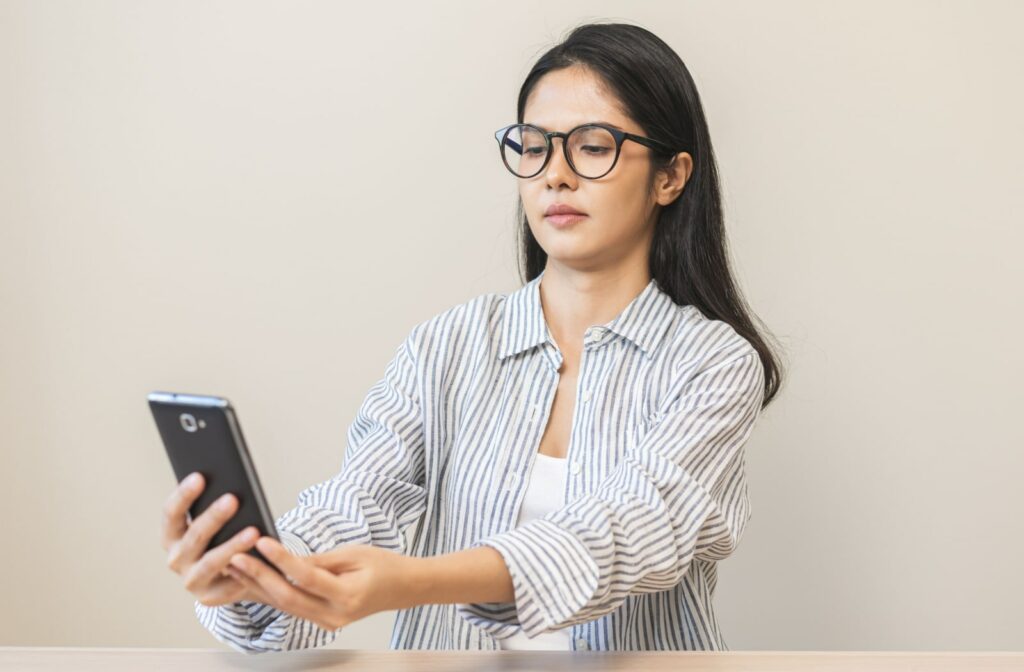 A woman with farsightedness holding her phone further away from her to read its content.