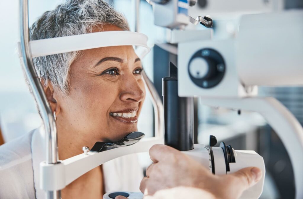 A senior woman during an eye exam smiling while getting checked for glaucoma.