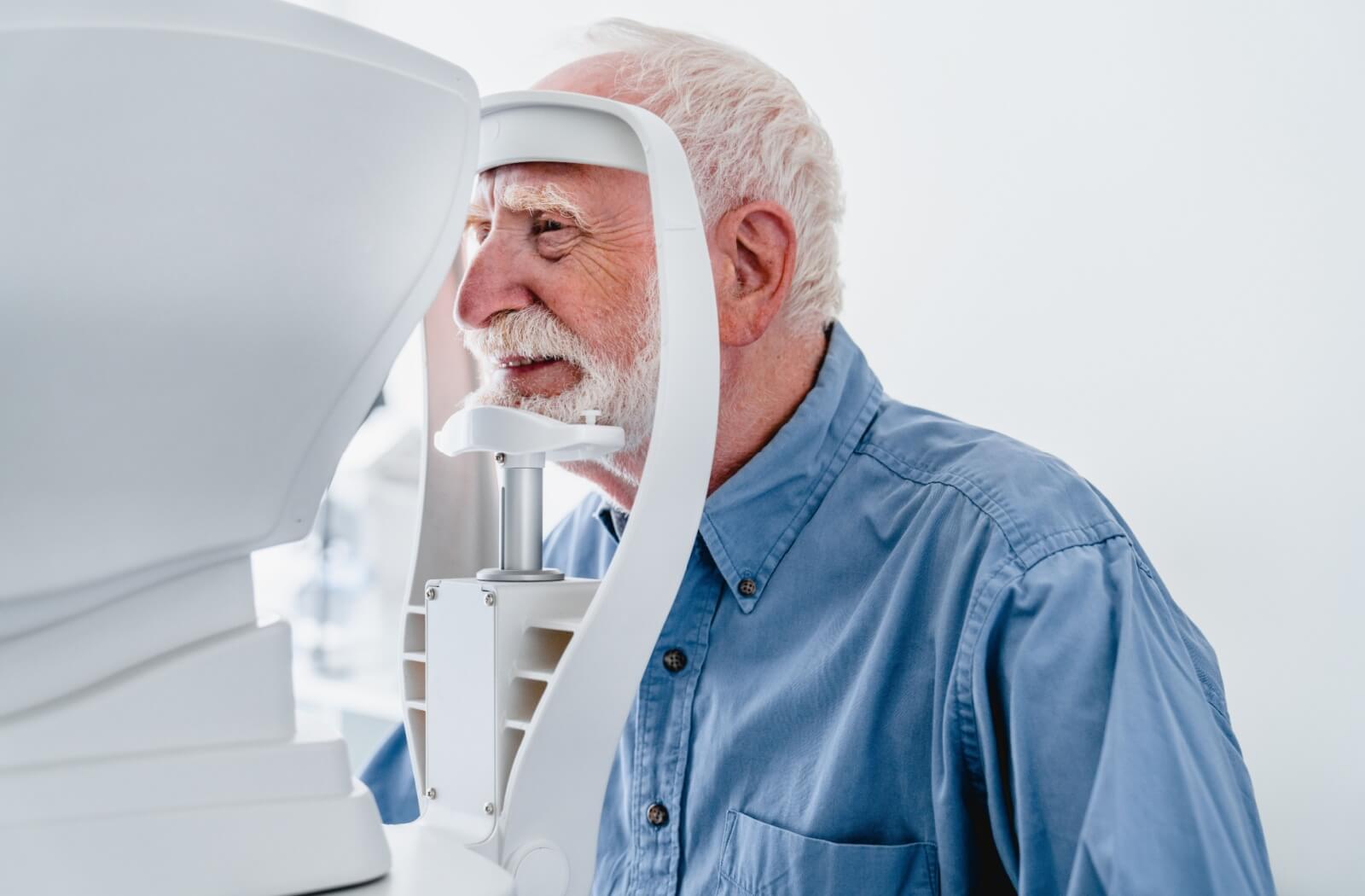 A smiling senior man at the optometrist's office being checked for glaucoma.