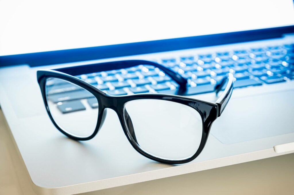 Close-up of black glasses sitting on a laptop.