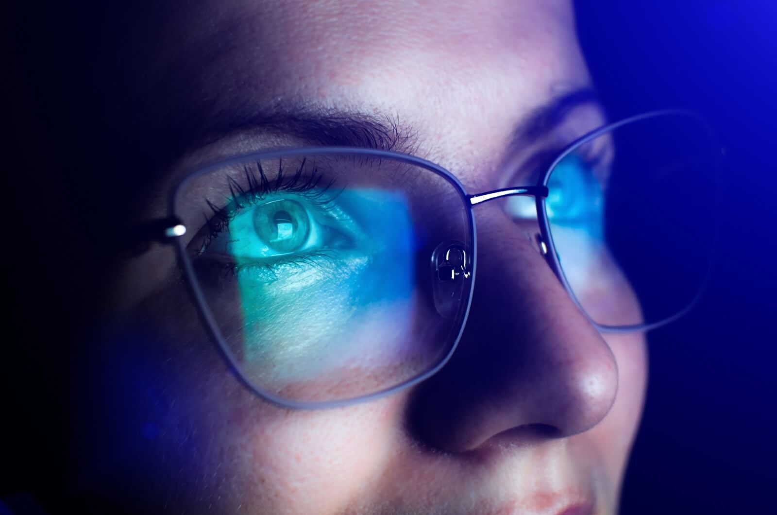 Close-up of blue light glare on a person's glasses.