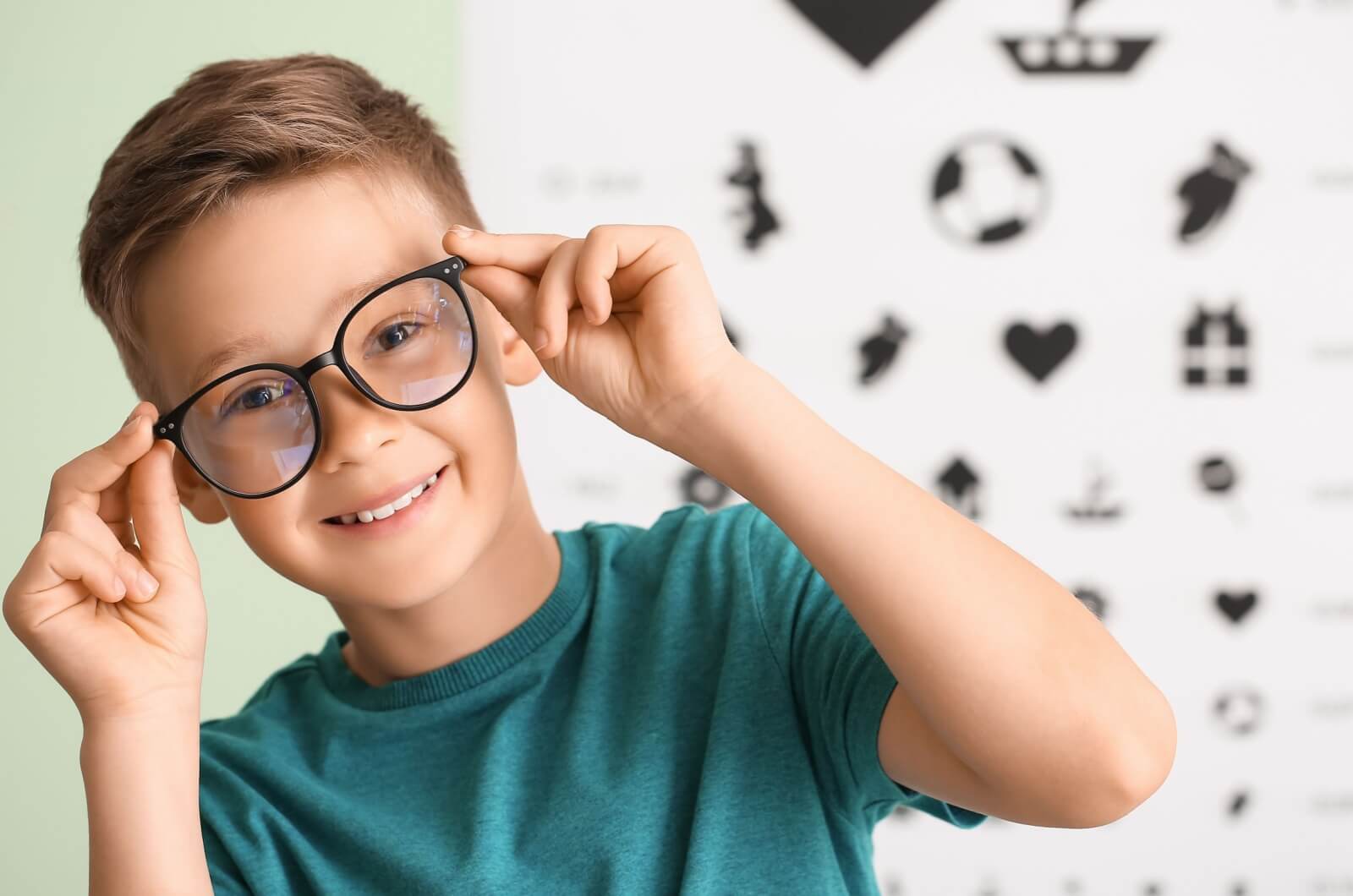 A young child happily enjoys wearing their glasses at the eye doctor.