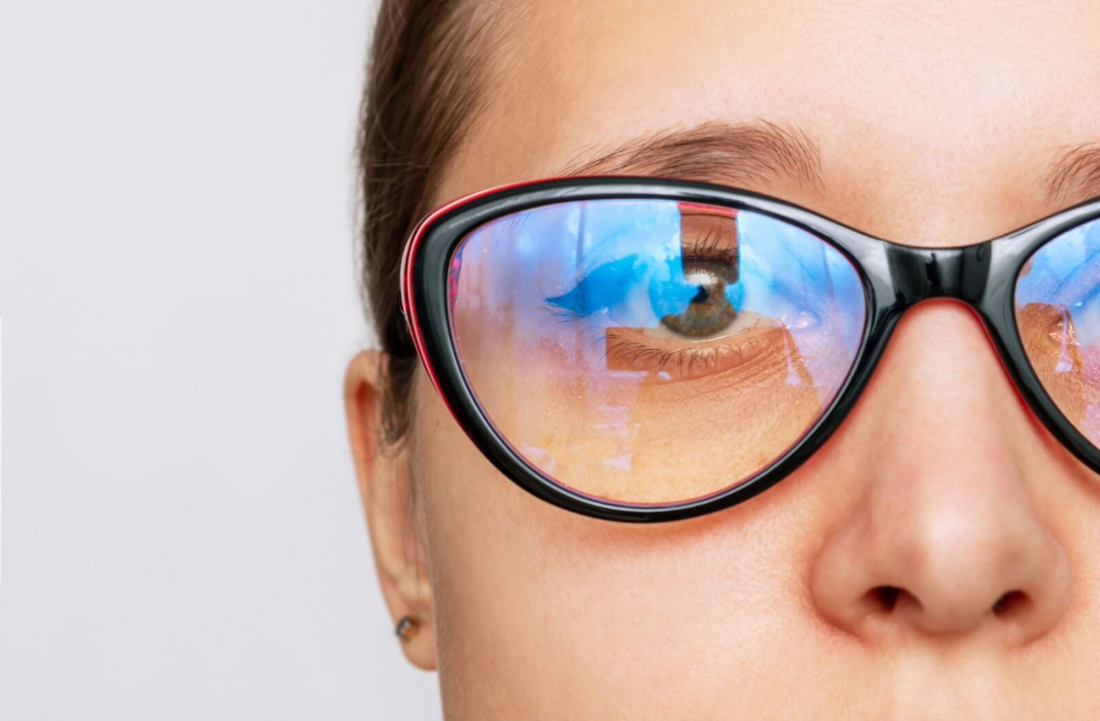 Close-up of reflective blue light on a person's eyeglasses, highlighting the lenses.