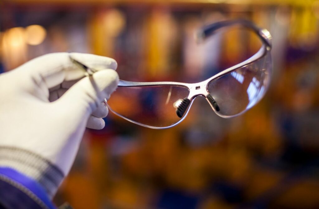 A person is holding a pair of Onguard safety glasses, showing their clear lenses.