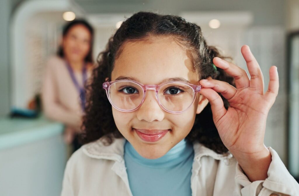 A smiling young patient in light pink glasses adjusts their new frames after receiving corrective lenses for nearsightedness (myopia).