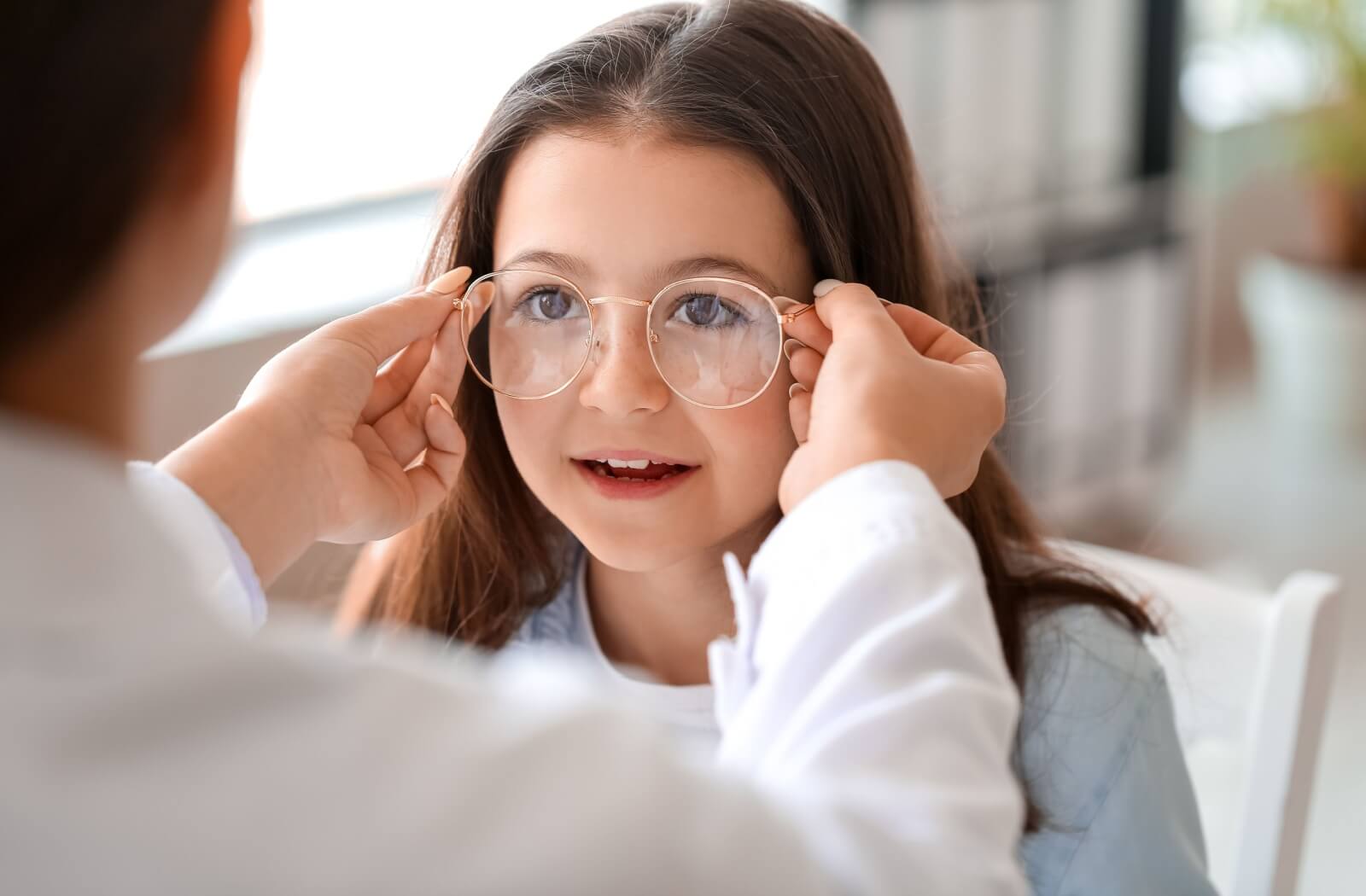 Eye care professional adjusting child’s glasses.