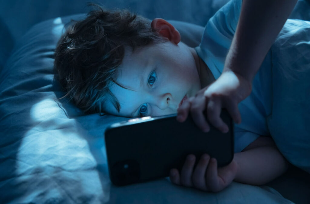 Child using a phone in bed.