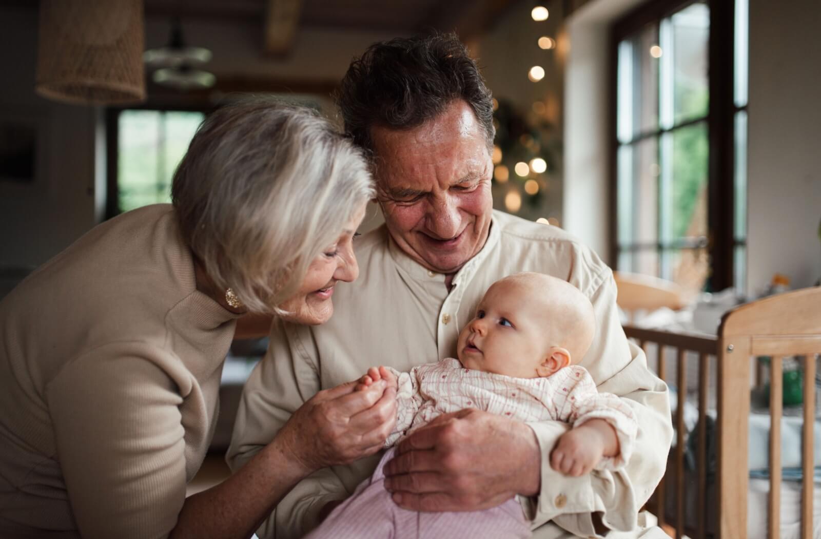 Two adults smiling while holding a baby, representing hereditary health.